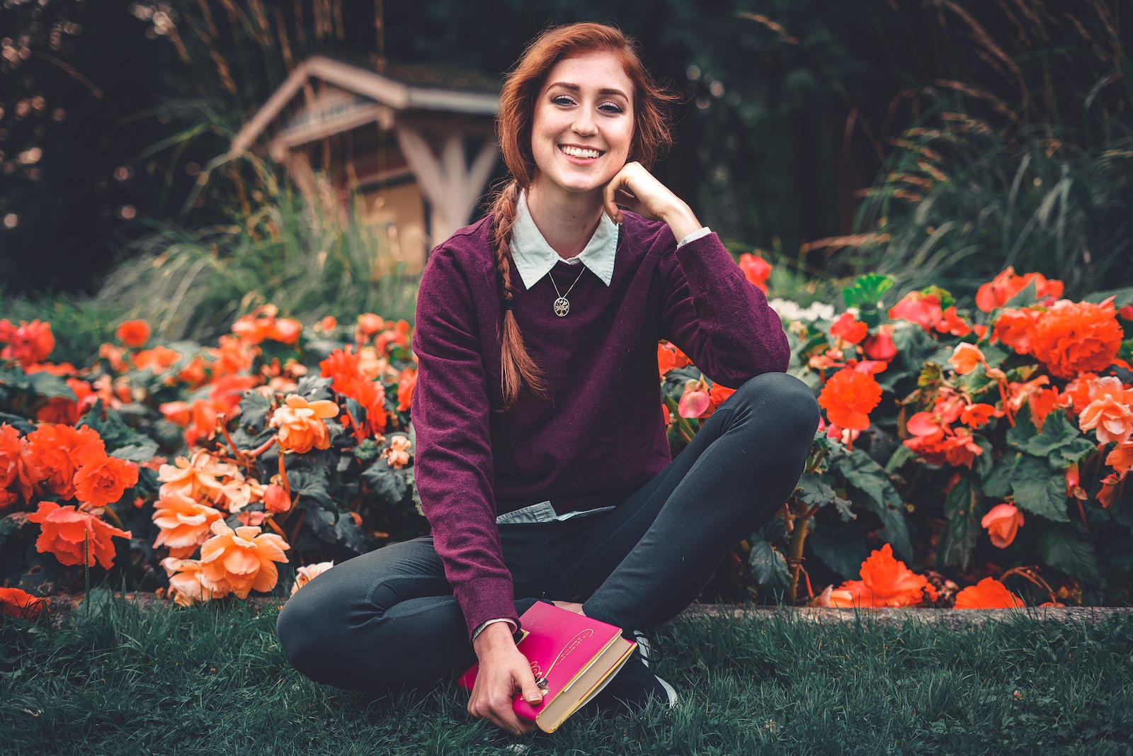 woman in red and black long sleeve shirt and black pants sitting on green grass field